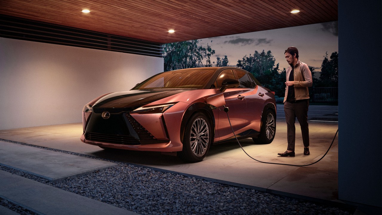 a man plugging a Lexus RZ 450e into a home charging station