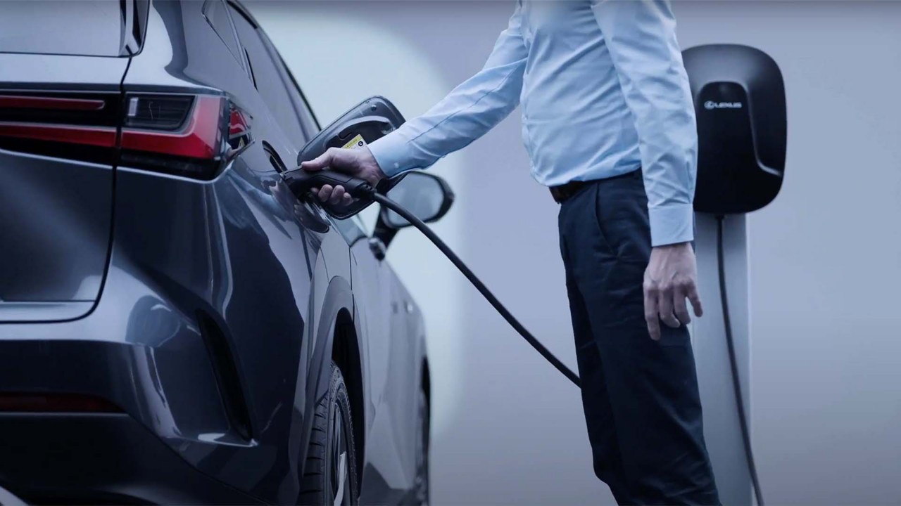 A man plugging in a home socket into a Lexus NX 450h+