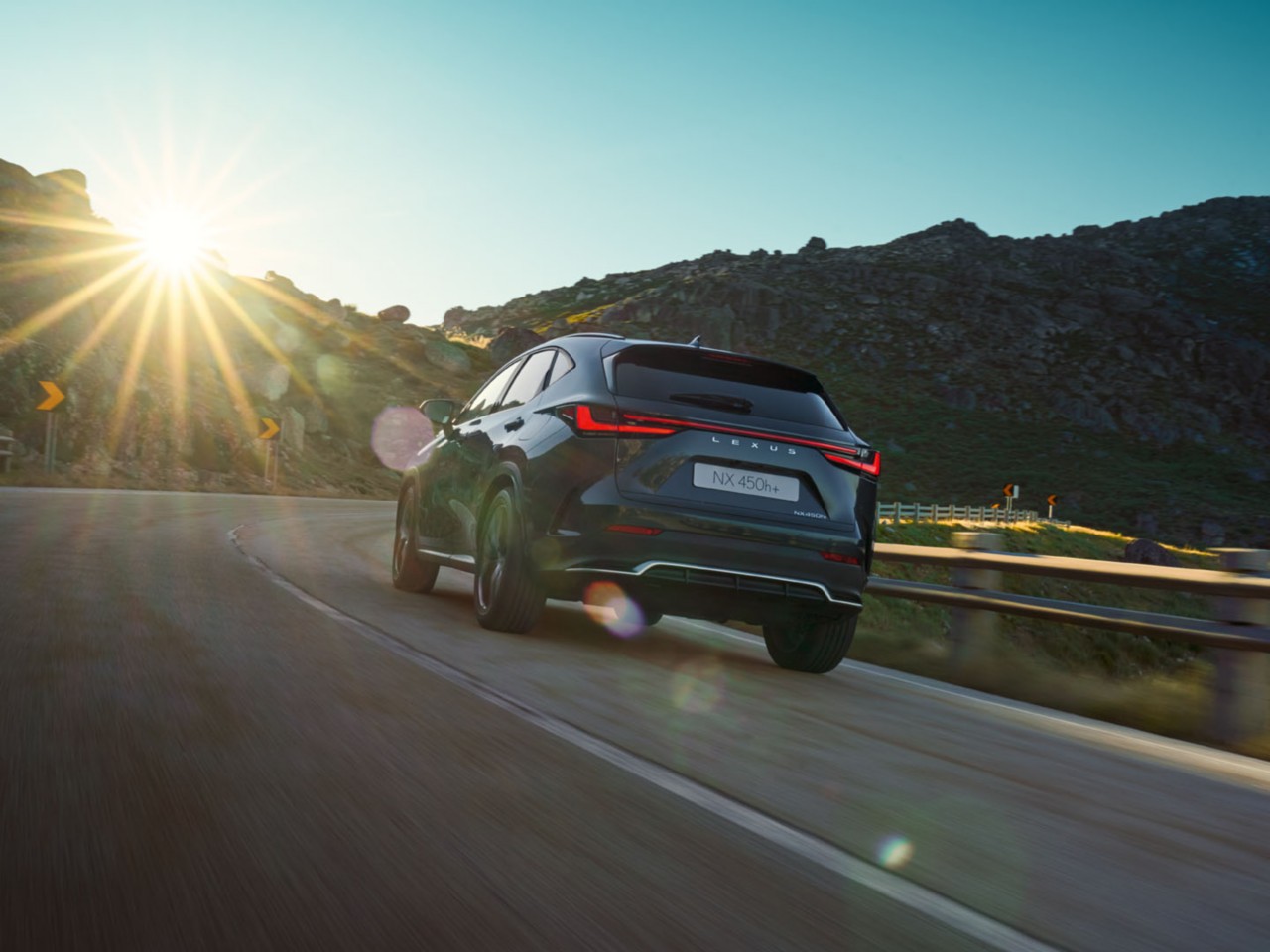 A rear view of the Lexus NX 450h+ driving 